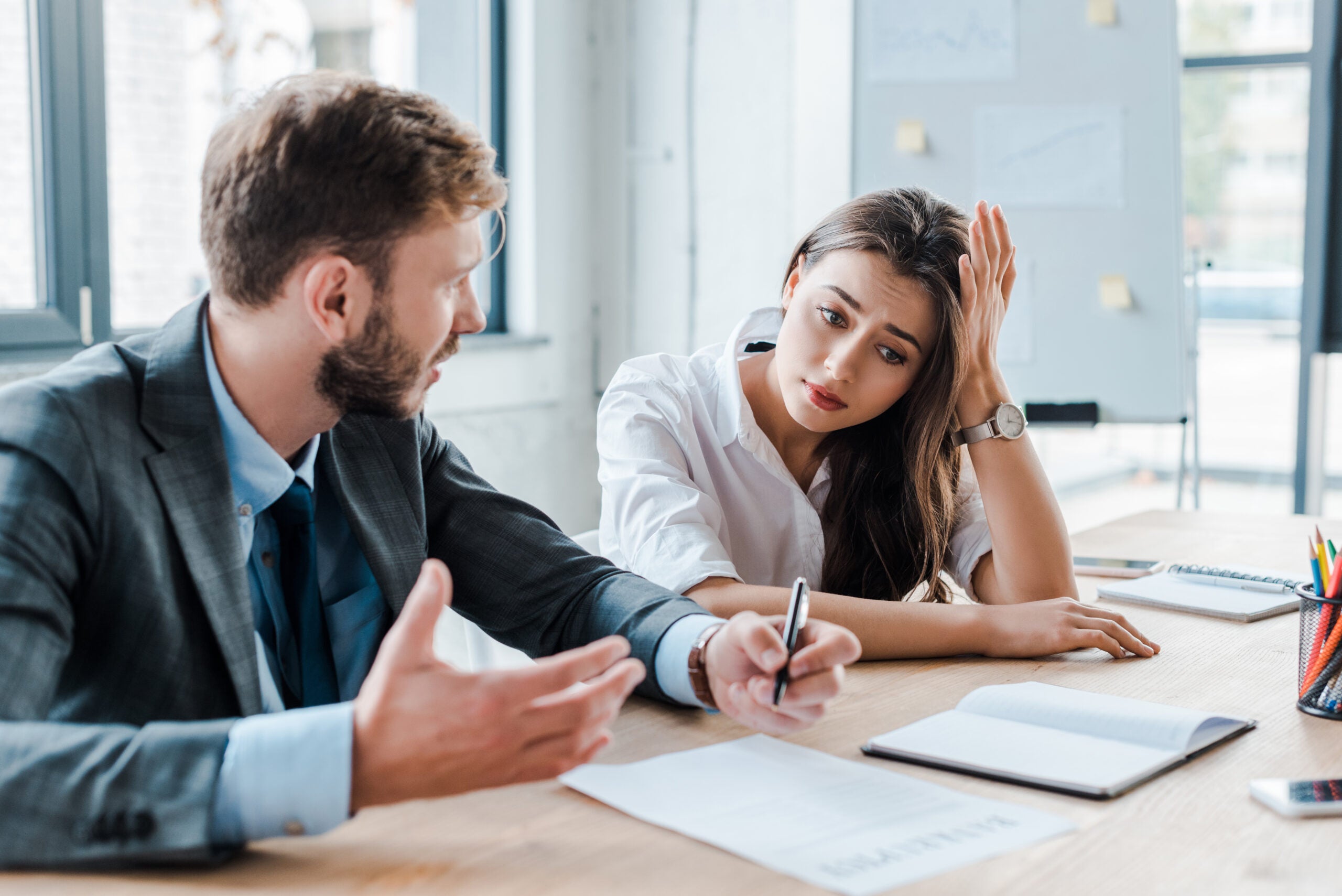 sad woman sitting with upset businessman in office