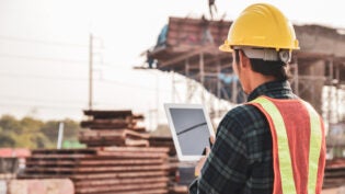 Construction engineers are using tablets to inspect construction projects on the background of the construction site.