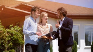 Property manager showing real estate purchase agreement to clients in house backyard