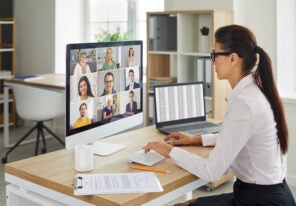 Woman sitting at office desk with computer during remote virtual business team meeting