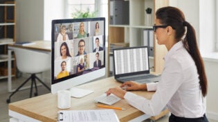 Woman sitting at office desk with computer during remote virtual business team meeting