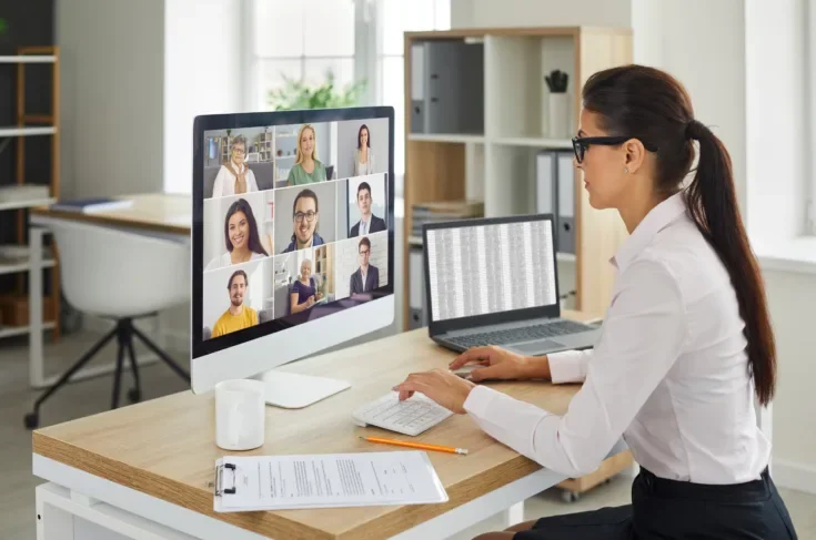 Woman sitting at office desk with computer during remote virtual business team meeting