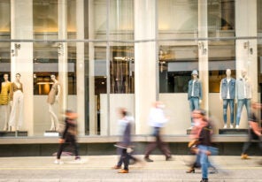 Motion blurred people walking past retail shop window on London