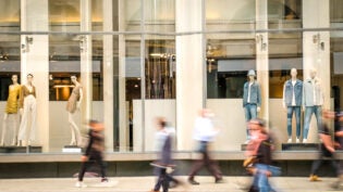 Motion blurred people walking past retail shop window on London