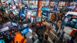 Group of attendees standing around a bustling convention hall at a tech conference or expo, showcasing innovation and excitement