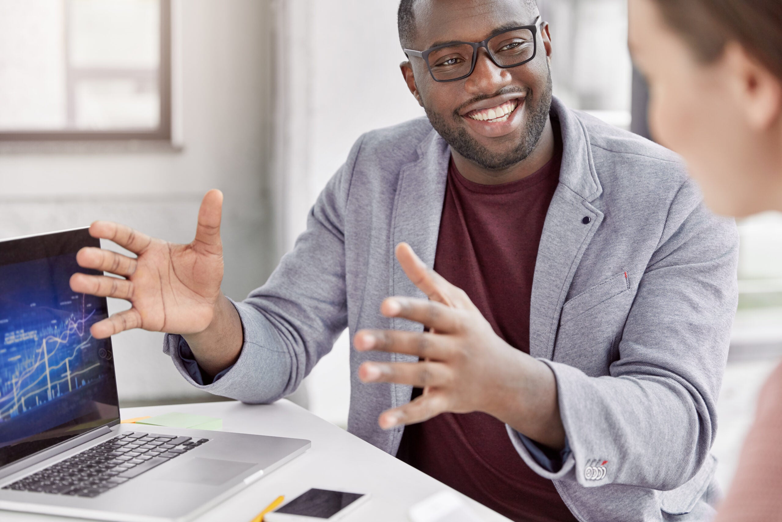 Cropped shot of black skilled professional marketing expert with cheerful expression makes speech during meeting with business partner, explains presentation and provides consultancy in office