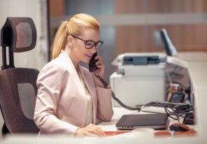 Young female receptionist talking on phone in office