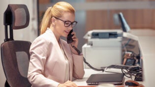 Young female receptionist talking on phone in office