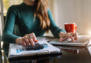 businesswoman working on desk office with using a calculator to calculate the numbers.