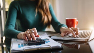 businesswoman working on desk office with using a calculator to calculate the numbers.