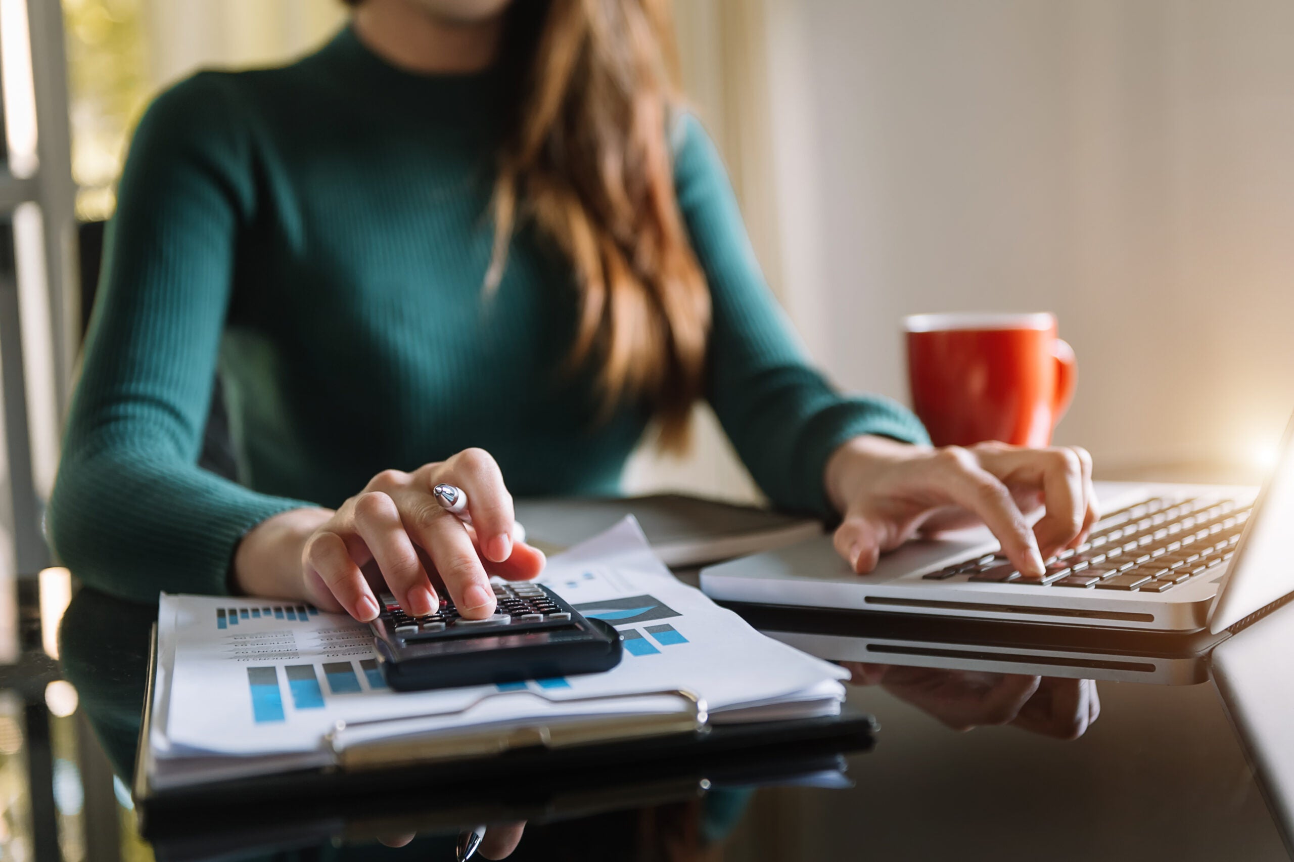 businesswoman working on desk office with using a calculator to calculate the numbers.