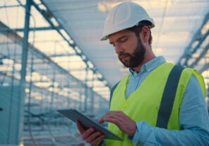 Factory worker with tablet inspecting new manufacture wearing green uniform