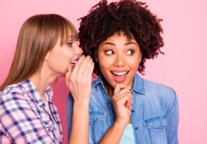 Woman whispering in ear of another woman