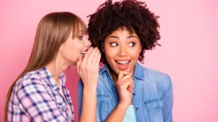 Woman whispering in ear of another woman