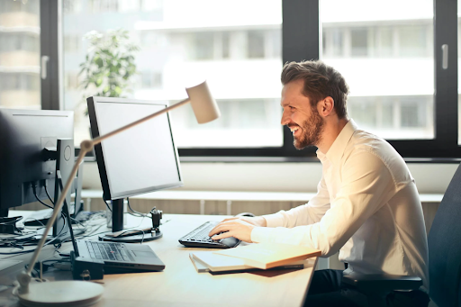 smiling bearded man typing at desk