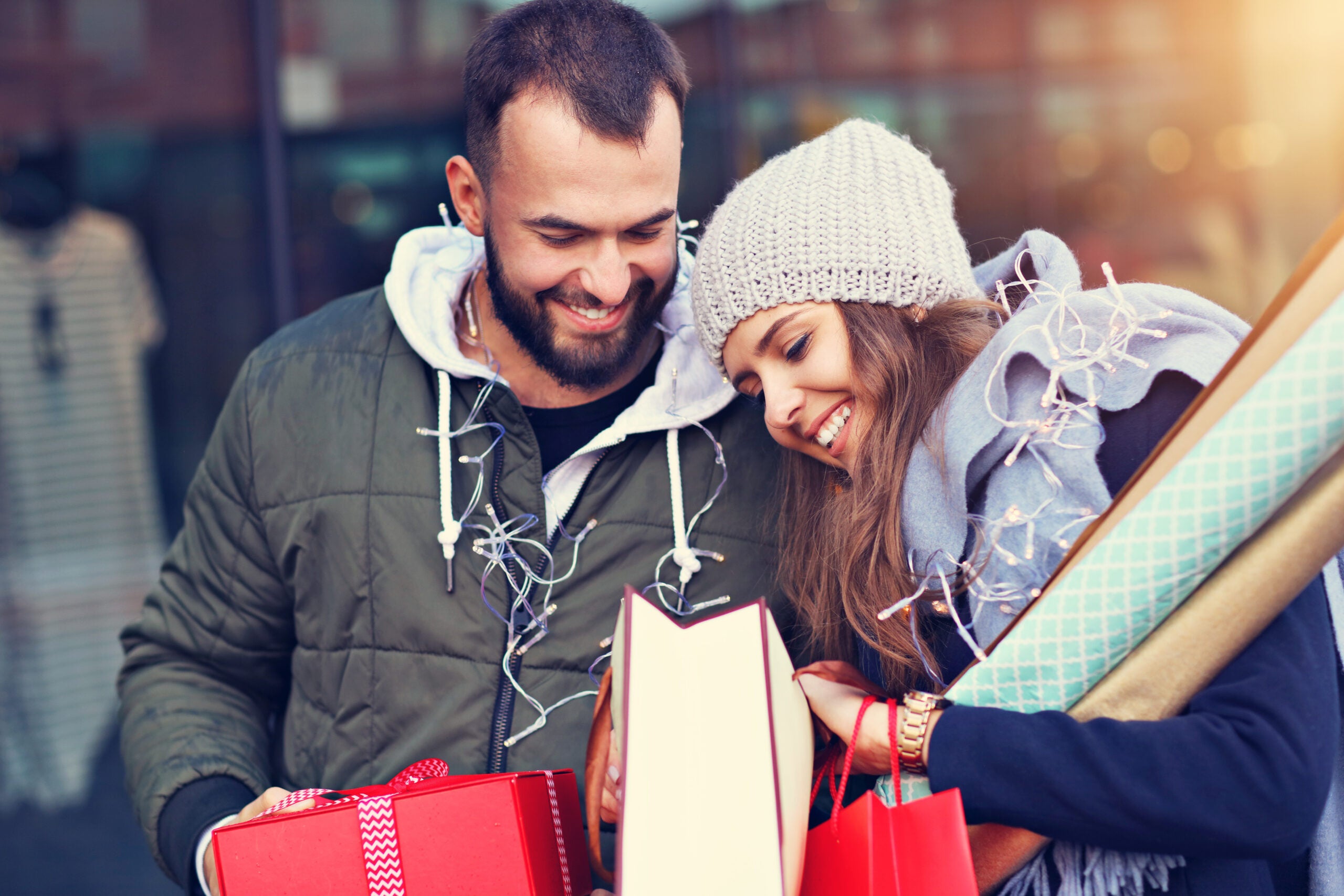 Portrait of happy couple with shopping bags after shopping in city smiling and huging