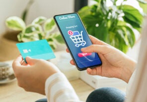 woman paying an order online with the phone and a credit card from home.