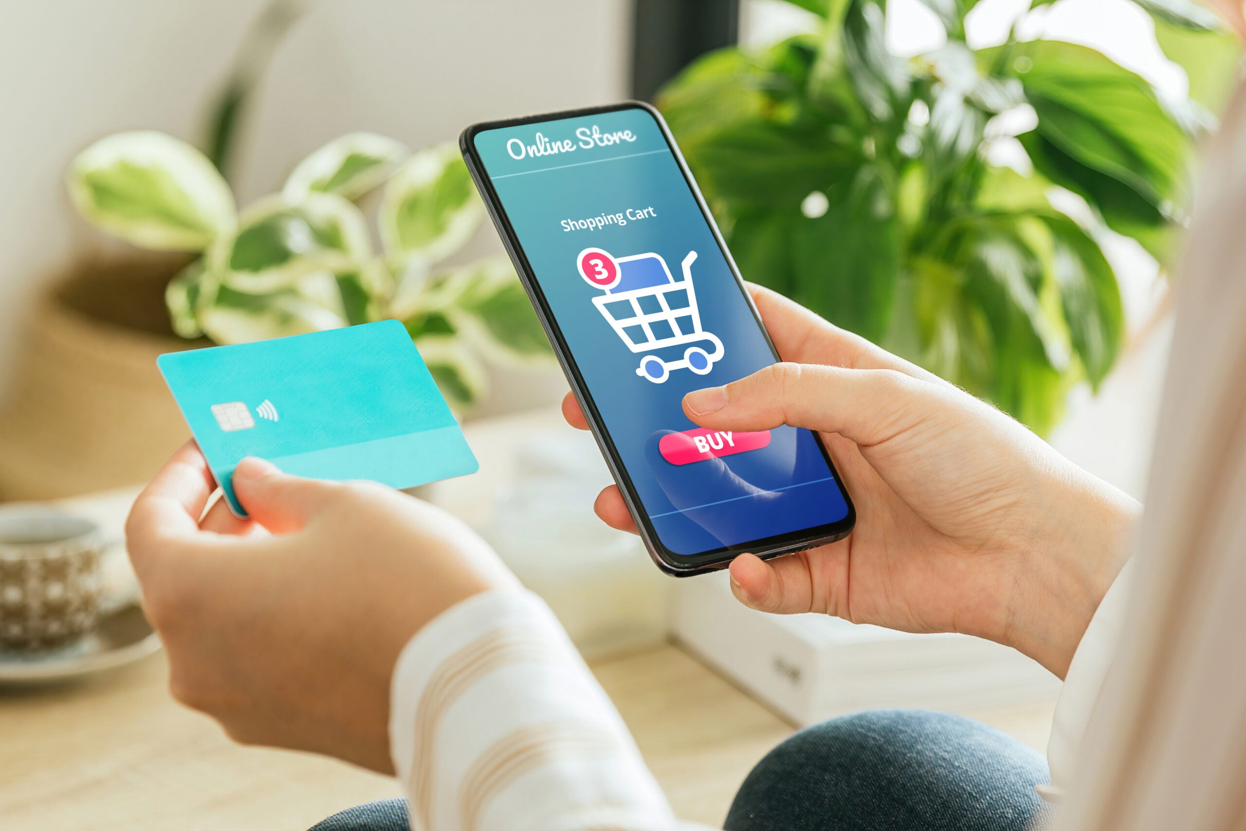 woman paying an order online with the phone and a credit card from home.