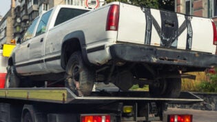 pickup vehicle accident transportation on flatbed tow truck machine on city street.