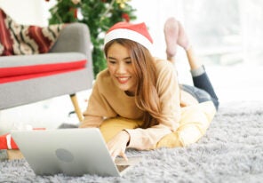 young asian woman on floor using laptop to search holiday promotion