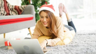 young asian woman on floor using laptop to search holiday promotion