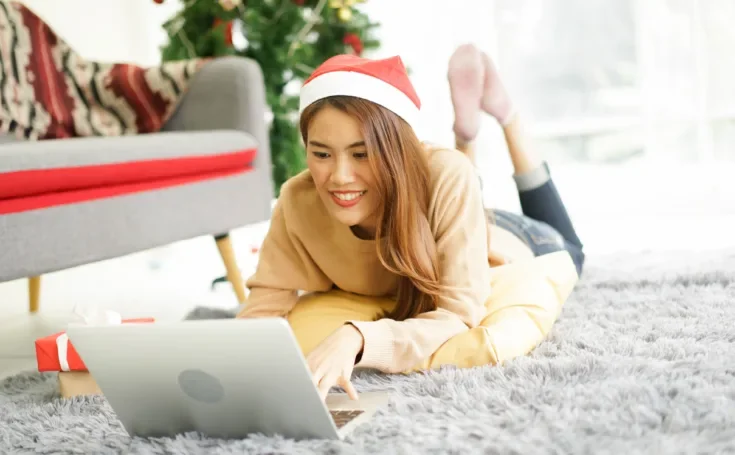 young asian woman on floor using laptop to search holiday promotion