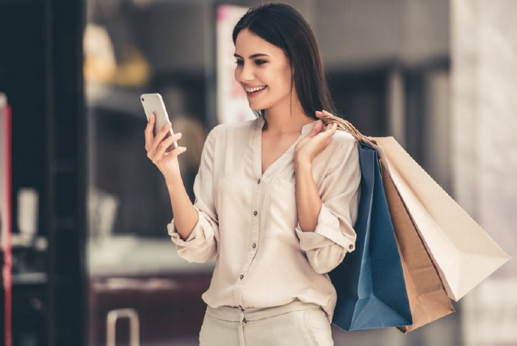 woman holding shopping bags and looking at phone