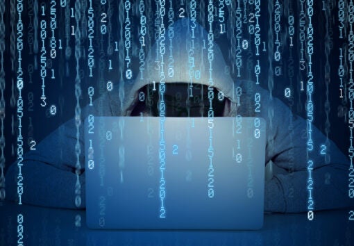 Young faceless man hacker working on a laptop on a binary code background