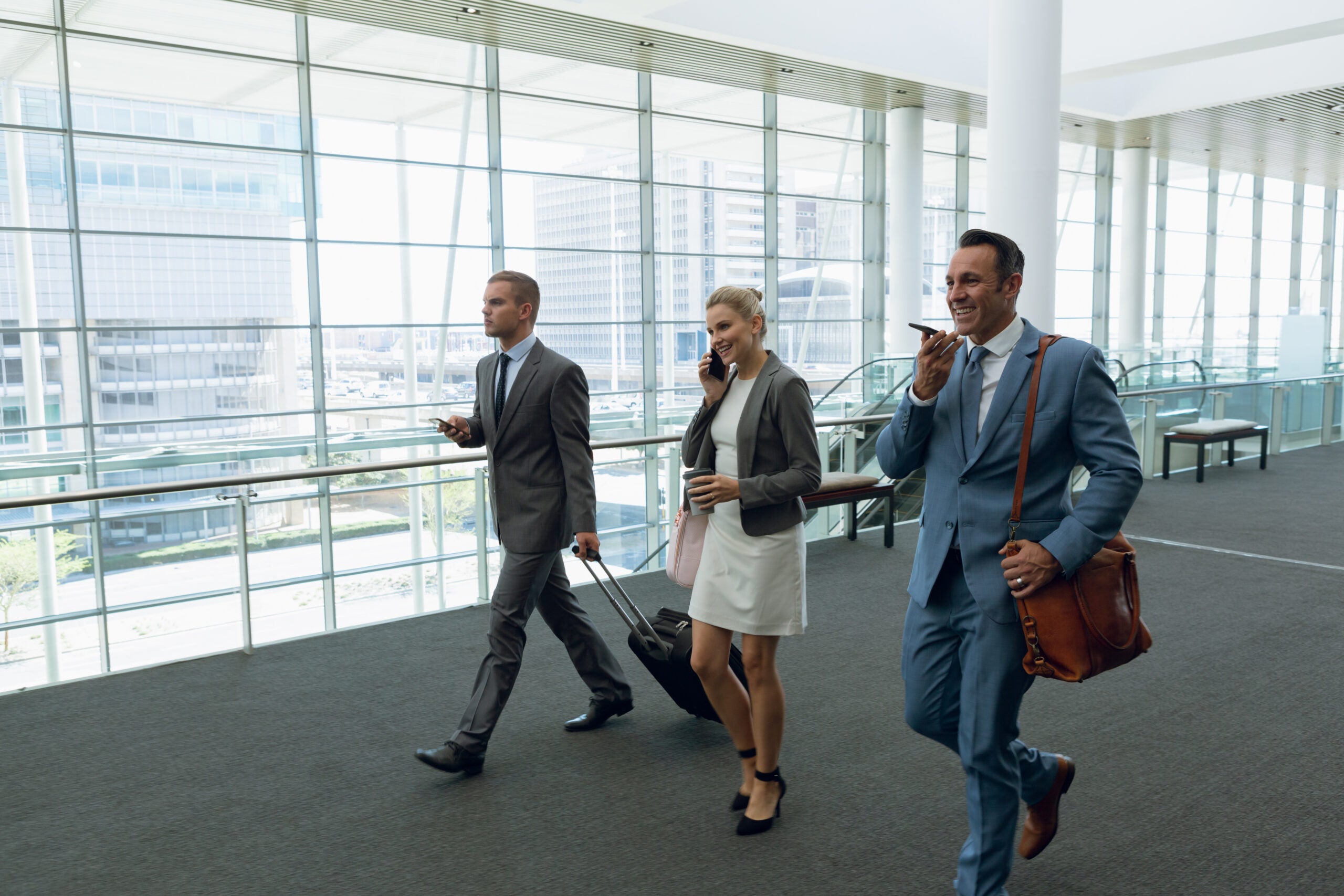 Business people talking on mobile phone while walking in the corridor