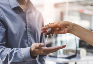 Close up view hands of agent giving car key to client