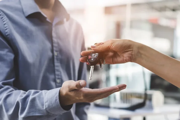 Close up view hands of agent giving car key to client