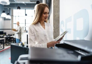 Young employee using modern printer in office