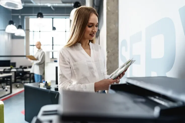 Young employee using modern printer in office