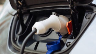 White electrical nozzle being plugged into e-car