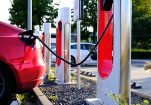 Tesla red passenger electric car replenishes battery at charging