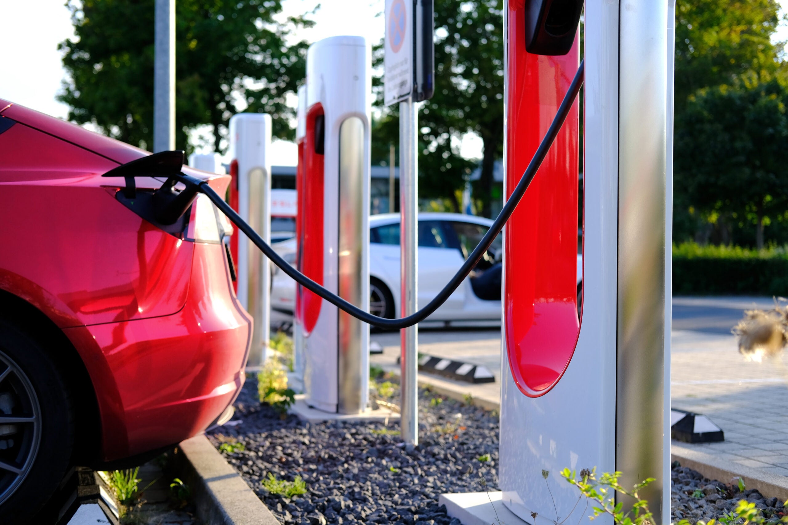 Tesla red passenger electric car replenishes battery at charging