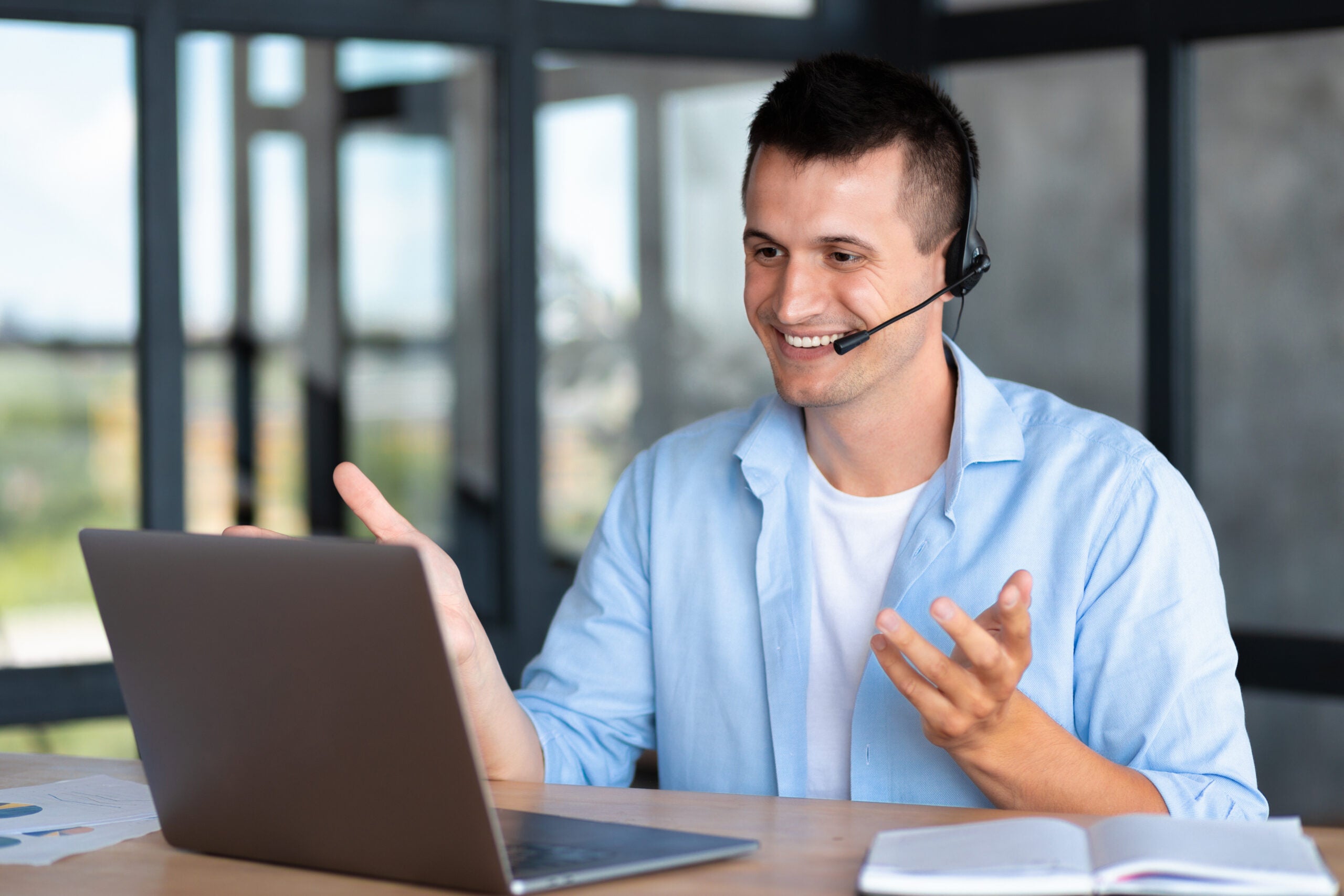 Happy caucasian employee call center, businessman, customer support manager wearing with headset using laptop computer for virtual meeting consulting client at on video call