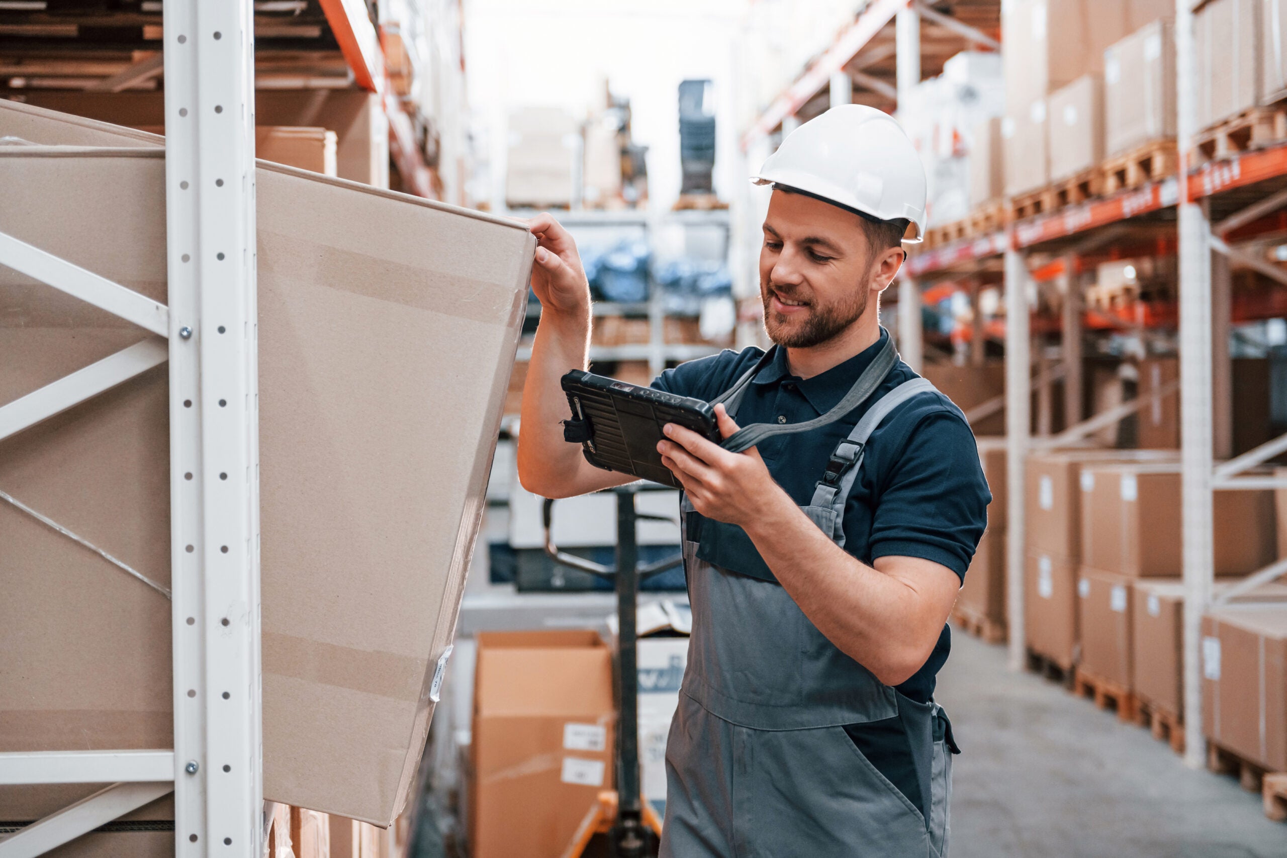 Checking the box. Employee in uniform is working in the storage at daytime.