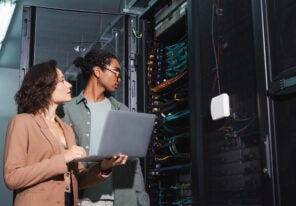 young engineers with laptop making diagnostics of server in data center