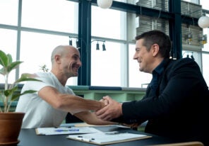 men shaking hands in office in partnership together