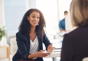 Interview with a happy, excited and confident human resources manager talking to a shortlist candidate for a job. Young business woman meeting with a colleague or coworker in her office at work