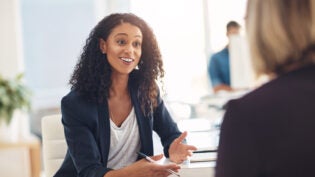 Interview with a happy, excited and confident human resources manager talking to a shortlist candidate for a job. Young business woman meeting with a colleague or coworker in her office at work