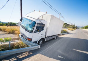 Crashed truck that hit crashed barrier on road, broken windshield, sunny day