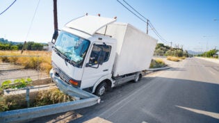 Crashed truck that hit crashed barrier on road, broken windshield, sunny day