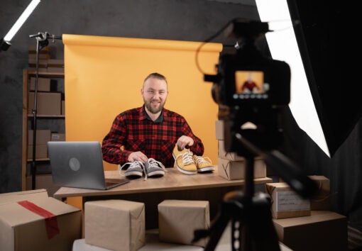 Millennial man blogger or vlogger looking at camera showing product for online store. Modern businessman using social media for marketing. Business online influencer blogger