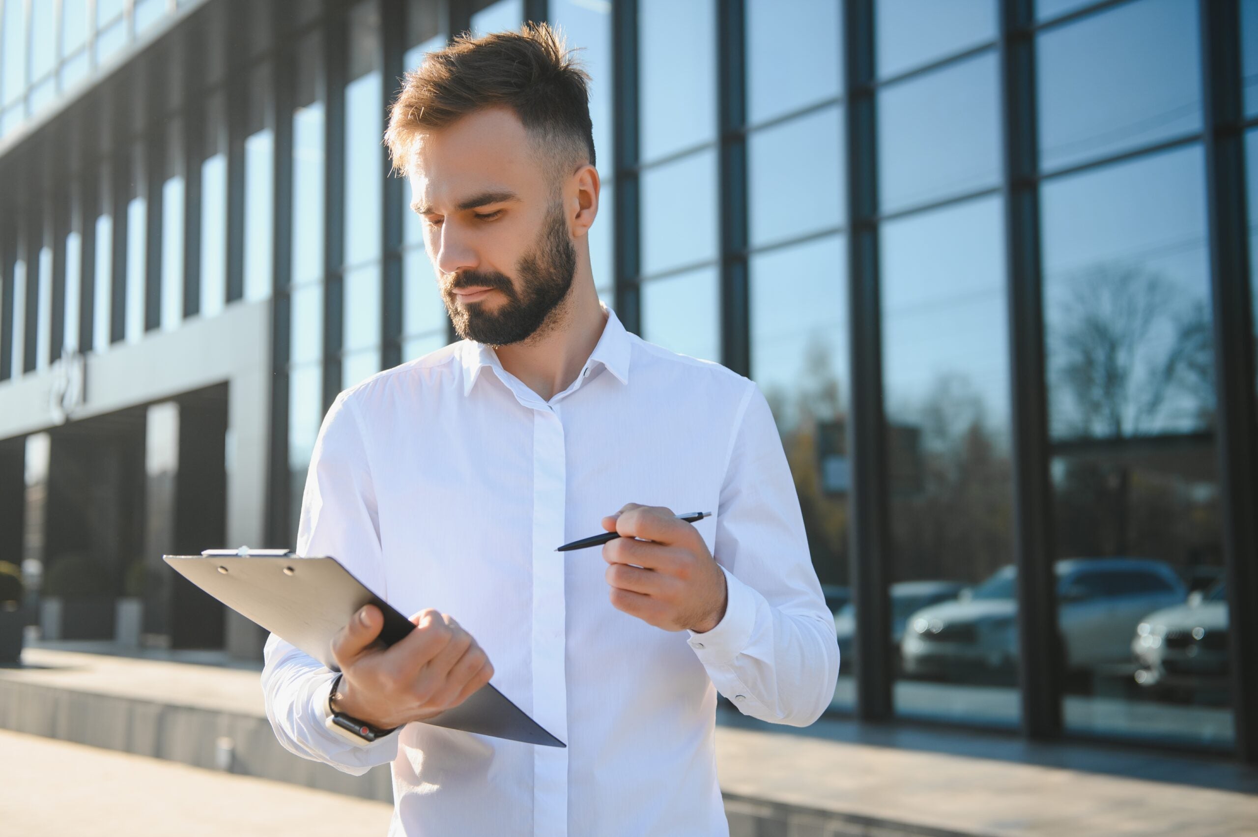 Male Realtor Standing Outside Residential Property Holding Keys Male Realtor Standing Outside Residential Property Holding Keys