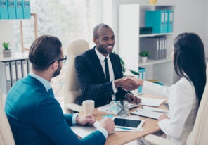 Partners making deal, shaking their hands, sitting in work place, wearing elegant, classic suits, to sign a contract, three professional, confident, stylish, attractive partners find a compromise