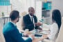 Partners making deal, shaking their hands, sitting in work place, wearing elegant, classic suits, to sign a contract, three professional, confident, stylish, attractive partners find a compromise