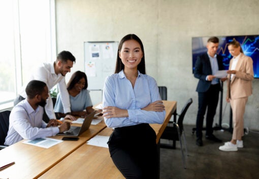 asian businesswoman standing in office, posing during corporate meeting in boardroom, korean female employee leaning on desk, standing with folded arms and smiling