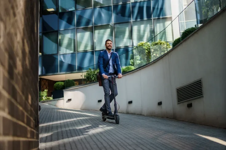 Young business man in a suit riding an electric scooter
